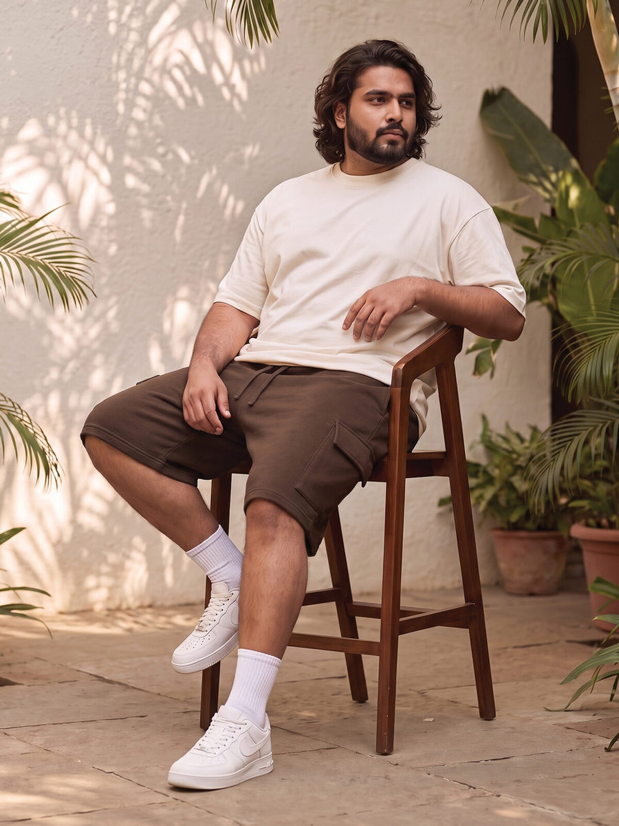 Fuller-build guy seated on a stool wearing brown cargo shorts