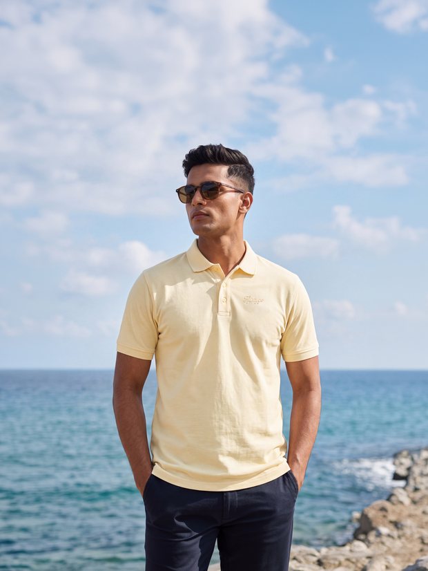 Man in a Butter Yellow PurEase polo on a seafront